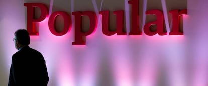 Un hombre pasa por delante de un rótulo antiguo de Banco Popular