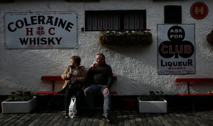 Aunque la ciudad continúa dividida en dos, atrae a cada vez más turistas, lo que ha hecho crecer las actividades comerciales y la hostelería. En la imagen, una pareja de turistas escoceses toman una bebida en la puerta del pub Duke of York, en Belfast.