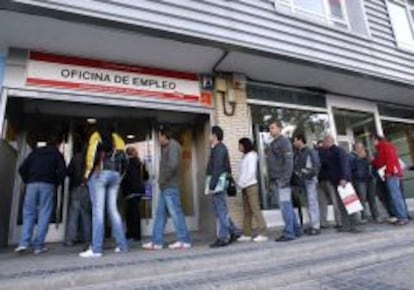 Una cola de personas delante de una oficina de empleo.