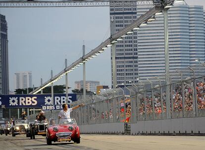 Los pilotos saludan a los aficionados del circuito de Marina Bay en un paseo en coches míticos