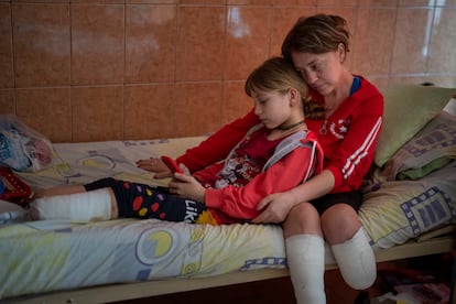 Natasha Stepanenko, de 43 años, sentada junto a su hija Yana, de 11, en un hospital público en Lviv. Yana perdió las dos piernas, una justo por encima del tobillo y la otra más arriba de la espinilla. Natasha perdió la pierna izquierda por debajo de la rodilla. (AP Photo/Emilio Morenatti) 