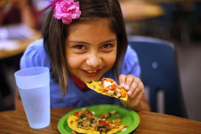 Niña comiendo pizza de verduras en EE UU.