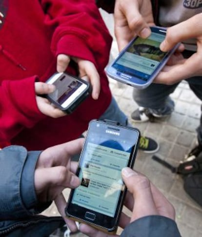 Three youngsters connect to the internet with their smartphones.