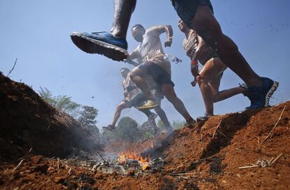 Los competidores de la Mud Race saltan sobre un obstáculo de fuego. Esta carrea se disputa en Kolad, India.