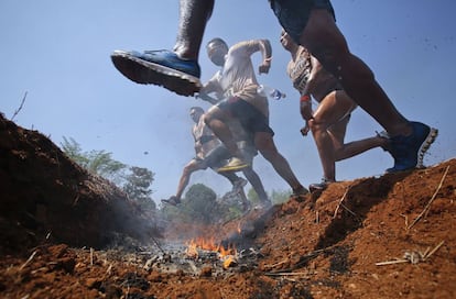 Los competidores de la Mud Race saltan sobre un obstáculo de fuego. Esta carrea se disputa en Kolad, India.