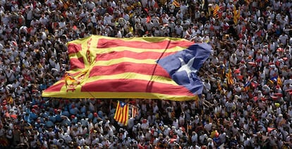 Una bandera estelada pasa entre las manos de los participantes a la Diada.