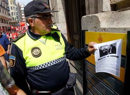 Un policía local retira un cartel con referencias a los casos de corrupción en la Comunidad Valenciana