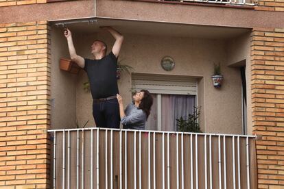 Una pareja arregla un toldo en un balcón, durante el confinamiento.