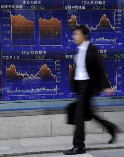 Un ejecutivo japonés camina frente a un tablero electrónico con los resultados de la Bolsa en Tokio, Japón. EFE/Archivo