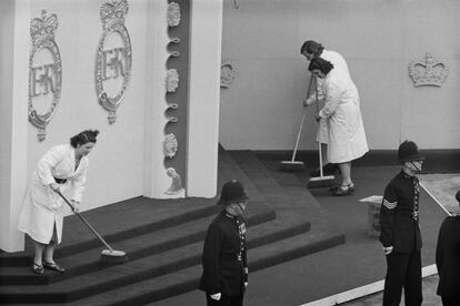 Un grupo de limpiadoras barriendo los escalones que conducen al anexo situado frente a la entrada oeste de la abadía de Westminster antes de la coronación de la reina Isabel. El anexo se utiliza como espacio para organizar las procesiones antes del servicio de coronación, y es conocido coloquialmente como la "suite de llegada y togas".