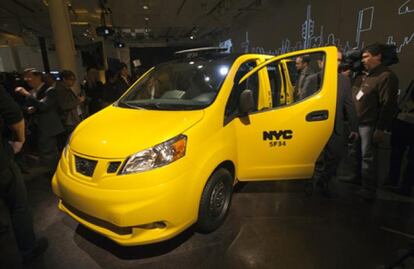 Periodistas y observadores rodean la camioneta Nissan NV200 taxi