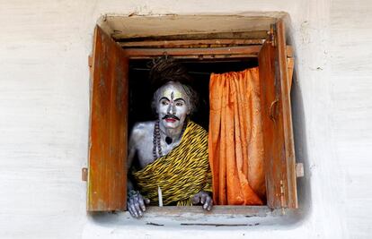 Un creyente vestido como el Dios hindú, Shiva, mira por la ventana mientras espera el inicio del festival Shiva Gajan a las afueras de Agartala (India).