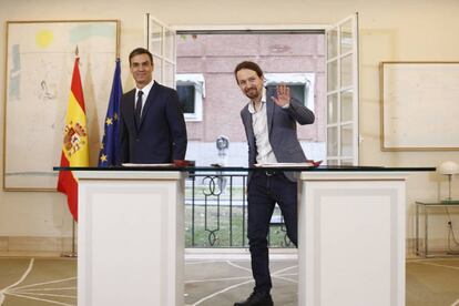 El presidente del Gobierno, Pedro Sánchez, firma con el secretario general de Podemos, Pablo Iglesias.