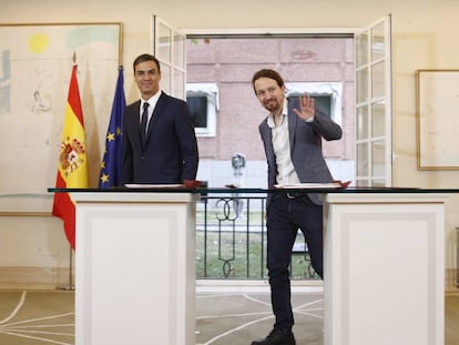 El presidente del Gobierno, Pedro Sánchez, firma con el secretario general de Podemos, Pablo Iglesias.