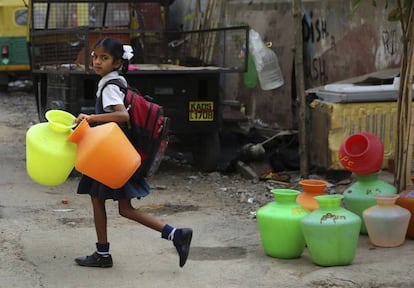 Una niña en Bangalore, India, con bidones vacíos para recoger agua después de salir de clase.