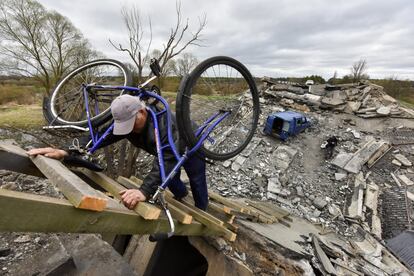 Un hombre carga una bicicleta a la espalda mientras sube una escalera de madera desde los restos de un puente que fue destruido en medio de la actual invasión rusa, cerca de Kiev. Casi cinco millones de personas han abandonado Ucrania desde el comienzo del conflicto, el 24 de febrero, según el último balance publicado este martes por ACNUR, la agencia para los refugiados de Naciones Unidas.