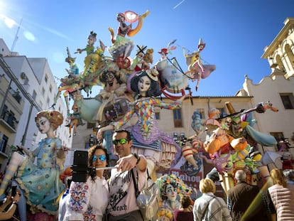 Una pareja se hace un selfie junto a una de las fallas.