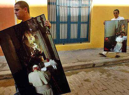 Dos obreros cubanos transportan fotografías, tomadas hace diez años, del fallecido papa Juan Pablo II, ayer en La Habana Vieja.