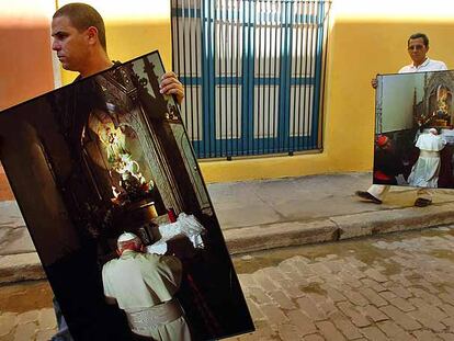 Dos obreros cubanos transportan fotografías, tomadas hace diez años, del fallecido papa Juan Pablo II, ayer en La Habana Vieja.