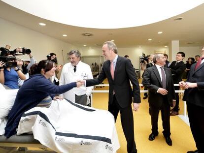 Alberto Fabra saluda a una mujer en la sala de rehabilitación y Alfonso Alonso mira al techo en la visita al hospital de Llíria.