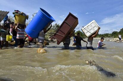 Colombianos deportados desde Venezuela cargan sus pertenencias a través del río Táchira.