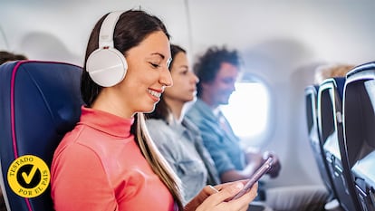 Una chica con auriculares y su móvil en un avión.