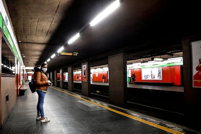 Una mujer protegida con una máscara espera en un solitario andén de una estación de metro, en Milán.