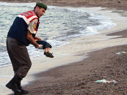 Un policía traslada el cadáver de un niño en una playa de Turquía. 