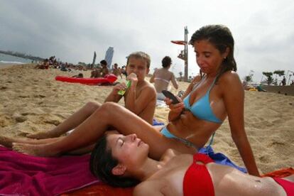 Varios veraneantes llaman por el móvil en la Playa del Calafell y Segur.