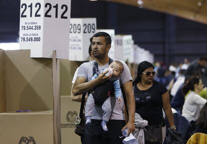 Un hombre que lleva a su bebé sale de la mesa principal de votación en Bogotá.