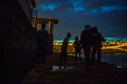 Un grupo de jóvenes migrados caminando por el espigón del puerto de la ciudad autónoma de Melilla.