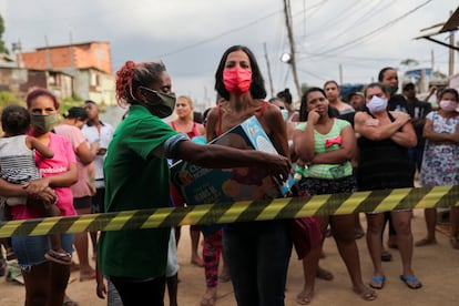 Una mujer recoge comida donada por una ONG este viernes en Brasilandia, una de las mayores favelas de São Paulo.