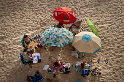 Un grupo de mujeres juega al bingo protegidas con sombrillas en la playa de La Caleta de Cádiz, durante estos días de ola de calor. 