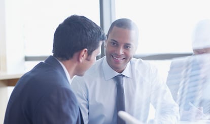 Dos hombres conversan durante una reunión.