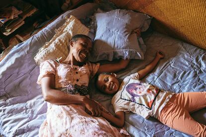 Joeline "Fara" Rafaraniriana y su hija, Odliatemix Rafaraniriana, descansan en la cama que comparten con su padre, Dada Paul Rakotazandriny, en su casa en Mandrosoa Ivato, Antananarivo (Madagascar).