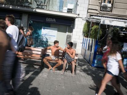 Dos turistes en banyador descansen en un banc de la Barceloneta.