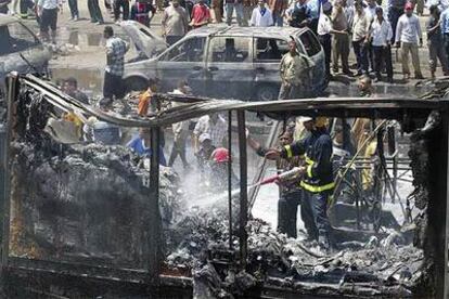 Unos bomberos apagan los restos de un camión incendiado por la explosión de un coche bomba en un concurrido mercado de Bagdad.