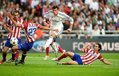 Gareth Bale do Real Madrid chuta a bola pressionado por Miranda e Tiago, do Atlético de Madrid.