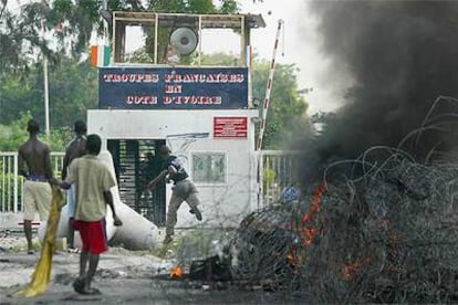 En la imagen, grupos de rebeldes atacan con piedras la base francesa en Abidjan.