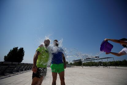 Varias personas se refrescan este jueves en el parque Juan Carlos I de Madrid.