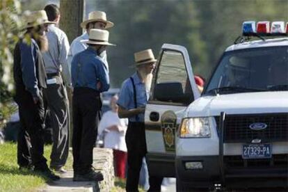 Un grupo de hombres amish conversa con un agente de policía cerca de la escuela de Georgetown (Pensilvania) en la que ayer se produjo el tiroteo.