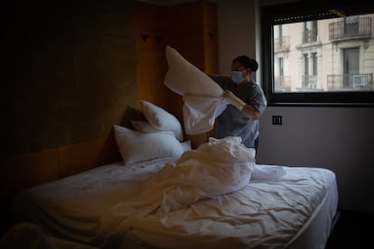 Una mujer hace la cama de un alojamiento en Cataluña.