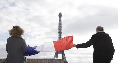Una bandera francesa hondea cerca de la Torre Eiffel durante el minuto de silencio celebrado en París (Francia).