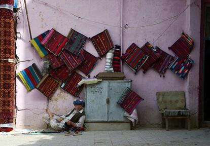 Un tendero afgano permanece sentado junto a su tienda de alfombras en Mazar-i-Sharif (Afganistán).
