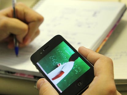 Estudante assiste a uma aula em vídeo pelo celular.