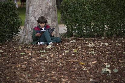 Un niño lee en una zona cercana a las casetas instaladas en el Retiro.