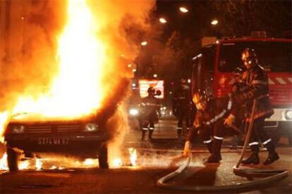 Los bomberos tratan de apagar un coche incendiado, el pasado día 7, en un barrio de Estrasburgo afectado por la revuelta.