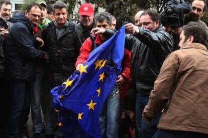 Un grupo de manifestantes quema una bandera de la UE durante la protesta de ayer en Atenas.