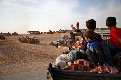 La ofensiva iniciada por las fuerzas turcas el 9 de octubre ha derivado en una crisis de desplazamiento que amenaza con forzar a 300.000 personas a abandonar sus hogares en las principales localidades de Hasaka y Raqqa. Más de 2.000 han llegado a la frontera con Irak e incluso han cruzado a territorio iraquí, según las organizaciones humanitarias. En la imagen, tres niños sirios muestran el signo de la victoria a los vehículos blindados turcos a las afueras de la ciudad de Manbij, en el norte de Siria.
