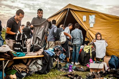 Un grupo de refugiados recogen ropa donada por la ONG eslovena ADRA en la frontera con Eslovenia.
